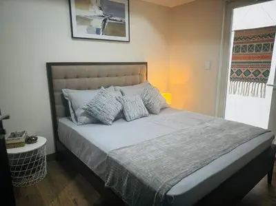 a bedroom with a large bed with pillows on it at 10G Cozy Condo at Park McKinley West near Venice Mall in Manila
