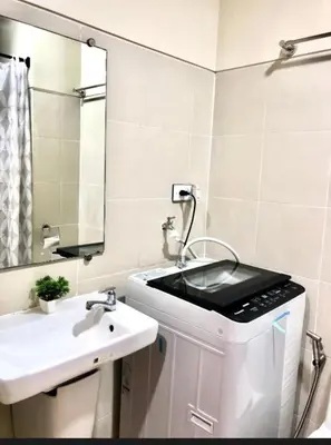 a white bathroom with a sink and a mirror at Kate's Place in Mall of Asia Complex in Manila