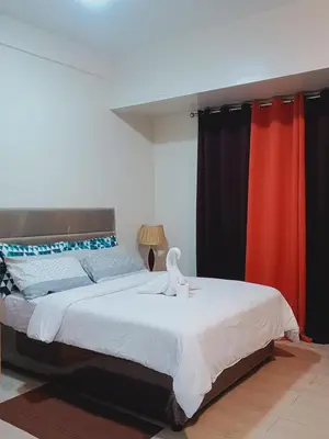 a bedroom with a large bed with red curtains at 81 Newport Boulevard-Hyuna Place, Across NAIA T3 in Manila