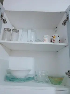 a shelf with glass dishes and bowls on it at 81 Newport Boulevard-Hyuna Place, Across NAIA T3 in Manila