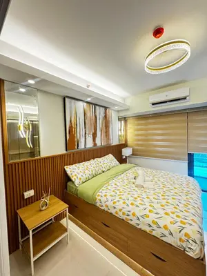 a bedroom with a large bed and a table at Grand Suites Shore 3 Residences in Manila