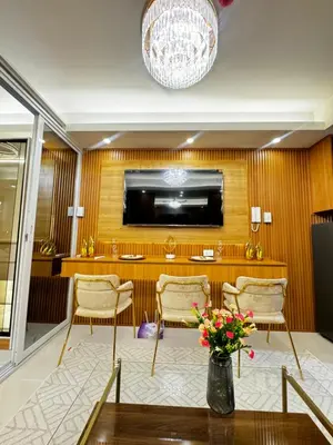 a room with a table and chairs and a television at Grand Suites Shore 3 Residences in Manila