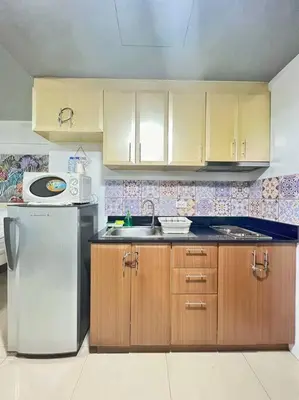 a kitchen with a stainless steel refrigerator and wooden cabinets at Nara Homes at Palm Tree Villas in front of NAIA Terminal 3 in Manila