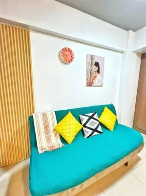 a blue couch with colorful pillows in a room at Nara Homes at Palm Tree Villas in front of NAIA Terminal 3 in Manila