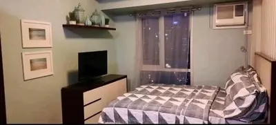 a bedroom with a bed and a television and a window at Avida San lorenzo Tower 1 Studio in Manila