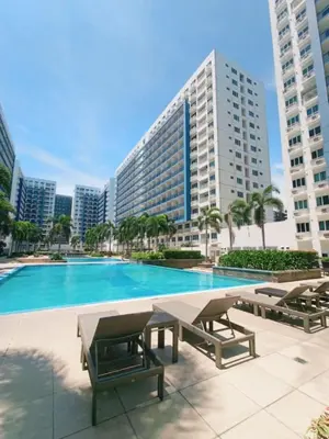 a pool with picnic tables and a large building at Sea Residences Karen's Staycation in Manila