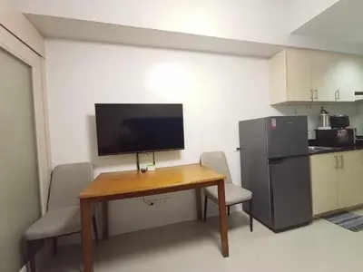 a kitchen with a table with chairs and a refrigerator at Sea Residences Karen's Staycation in Manila