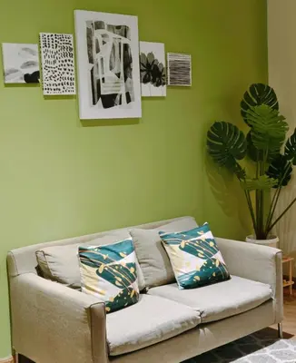 a couch in a living room with green walls at Christine Suites PH 1BR with Balcony Gramercy Residences Makati in Manila