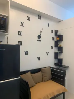 a room with a couch and a clock on the wall at Smdc south Residences almanza uno in Manila