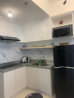 a kitchen with white cabinets and a black refrigerator at Smdc south Residences almanza uno in Manila