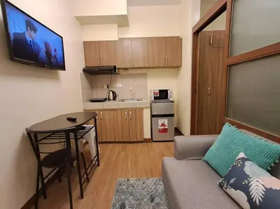 a living room with a couch and a table and a kitchen at Cozy Home beside mall,MRTBoniEDSA in Manila