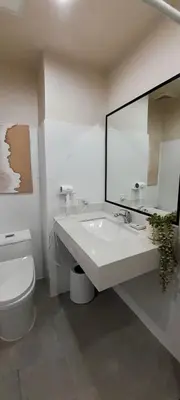 a bathroom with a sink and a toilet and a mirror at La Nobleza Manila in Manila