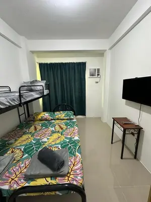 a room with two bunk beds and a flat screen tv at B&CH RESIDENCE Transient in Calamba