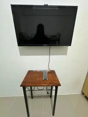 a television hanging on a wall with a wooden table at B&CH RESIDENCE Transient in Calamba