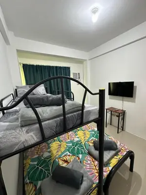 a bedroom with two bunk beds and a flat screen tv at B&CH RESIDENCE Transient in Calamba