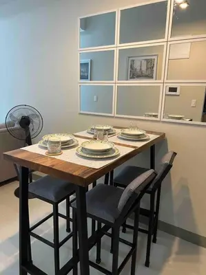a wooden table with chairs and plates on it at Condo at the heart of BGC located at Uptown Parksuites in Manila