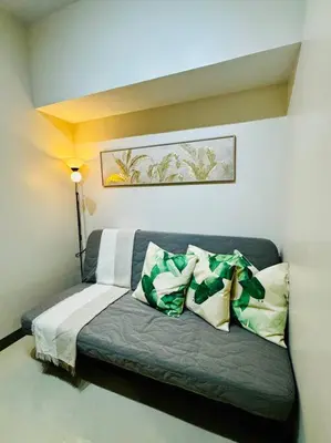 a couch with pillows on it in a room at 10F Luxury 1BR at Park Mckinley West near Venice Mall in Manila