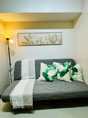 a couch with pillows on it in a room at 10F Luxury 1BR at Park Mckinley West near Venice Mall in Manila