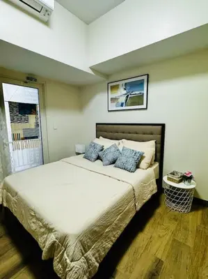 a bedroom with a large bed with blue pillows at 10F Luxury 1BR at Park Mckinley West near Venice Mall in Manila