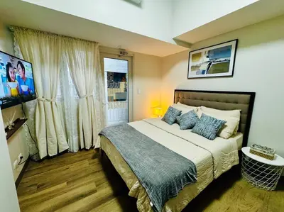 a bedroom with a large bed and a window at 10F Luxury 1BR at Park Mckinley West near Venice Mall in Manila