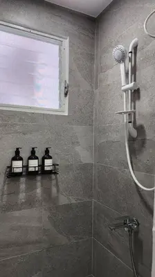 a bathroom with a shower with three bottles in it at Boudoir Hideaway close to Araneta Center in Manila