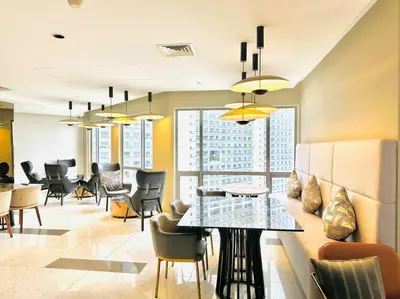 a dining room with a table and chairs and windows at The Hotel at Acqua Residences Tower 2 in Manila