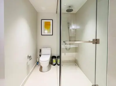 a bathroom with a toilet and a glass shower at The Hotel at Acqua Residences Tower 2 in Manila