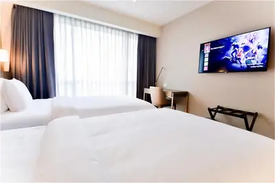 a hotel room with two beds and a flat screen tv at The Hotel at Acqua Residences Tower 2 in Manila