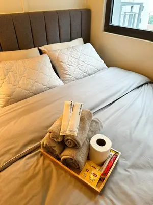 a tray with towels and toilet paper on a bed at Cozy and Aesthetic Condo at Shore 3 in MOA, Pasay in Manila