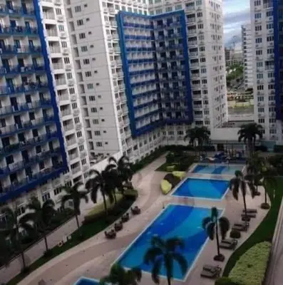 an overhead view of a pool with palm trees and buildings at Sea Residences by-Azenith in Manila