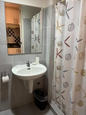 a bathroom with a sink and a shower curtain at Sea Residences by-Azenith in Manila