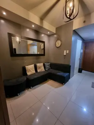 a living room with a black couch and a mirror at Shell Residences - 1 br no balcony in Manila
