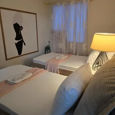 a bedroom with two beds with a lamp and a picture of a woman at Coquette vibes close to Cubao's Araneta Center in Manila