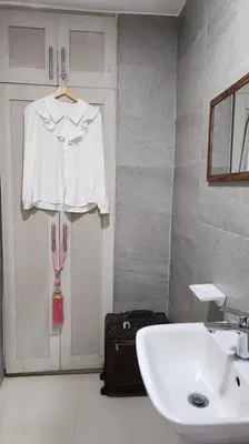 a bathroom with a sink and a white shirt on a door at Coquette vibes close to Cubao's Araneta Center in Manila