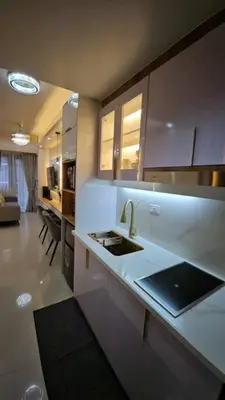 a kitchen with a sink and a living room at Cozy apartment near Airport in Shore 3 in Manila