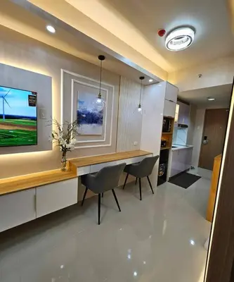 a living room with a table and chairs and a television at Cozy apartment near Airport in Shore 3 in Manila