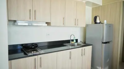 a kitchen with a sink and a refrigerator at SM Breeze one bedroom in Manila