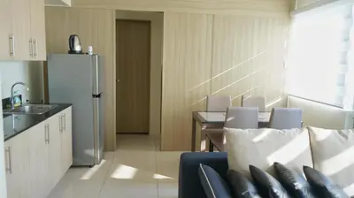 a kitchen with a refrigerator and a table and chairs at SM Breeze one bedroom in Manila