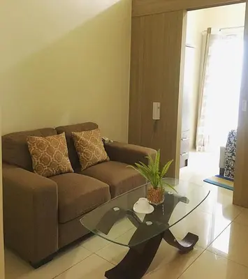 a living room with a couch and a glass table at SM Breeze one bedroom in Manila