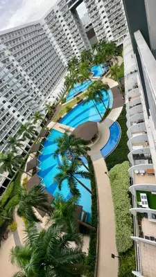 an aerial view of a building with pools and palm trees at Kathys Crib with balcony Pool view at Shell Residence in Manila