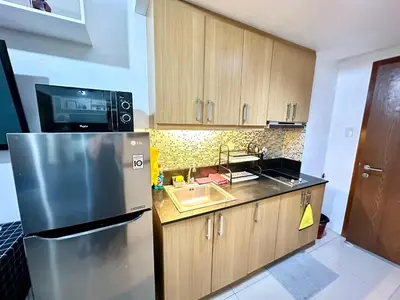 a kitchen with a stainless steel refrigerator and a sink at Kathys Crib with balcony Pool view at Shell Residence in Manila