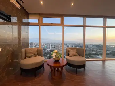 a living room with two chairs and a table and a large window at Coast Residences Near MOA and NAIA Manila Bay View with Pool in Manila