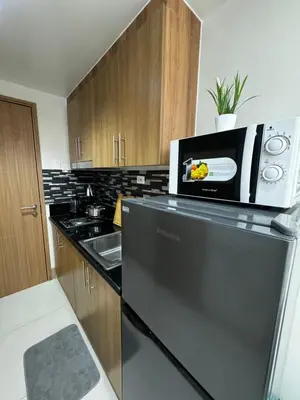 a kitchen with a microwave on top of a refrigerator at Bachelor Pad Shore 3 Residences in Manila
