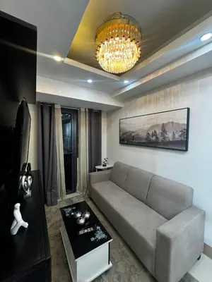 a living room with a couch and a chandelier at Bachelor Pad Shore 3 Residences in Manila