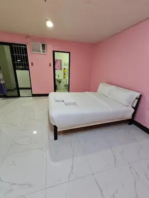 a bedroom with a white bed in a pink wall at cartimar hotel condo in Manila