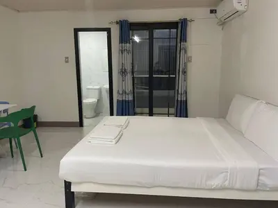 a white bed in a room with a bathroom at cartimar hotel condo in Manila