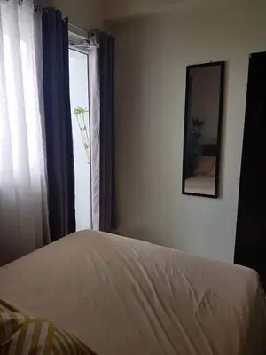 a bedroom with a bed and a mirror and a window at SkyViewCondotel Breeze Residences Staycation near WTC,PICC,MOA,NAIA,OCEAN PARK in Manila