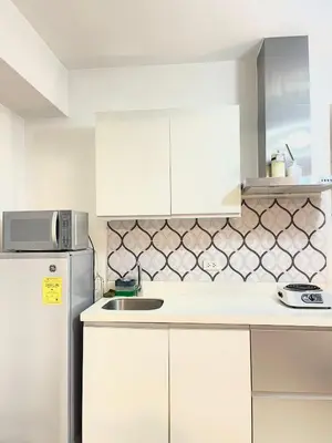 a kitchen with white cabinets and a refrigerator at azure urban resort residences in Manila