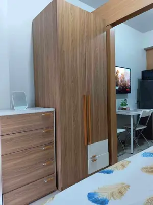 a bedroom with a large wooden cabinet and a desk at Shell Residences Condotel Apartment in Manila