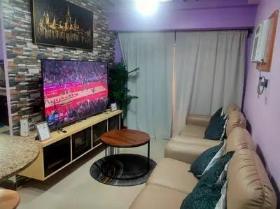 a living room with a couch and a flat screen tv at Near Manila Airport COZY 02 Bedroom Condo With Pool - 4R in Manila